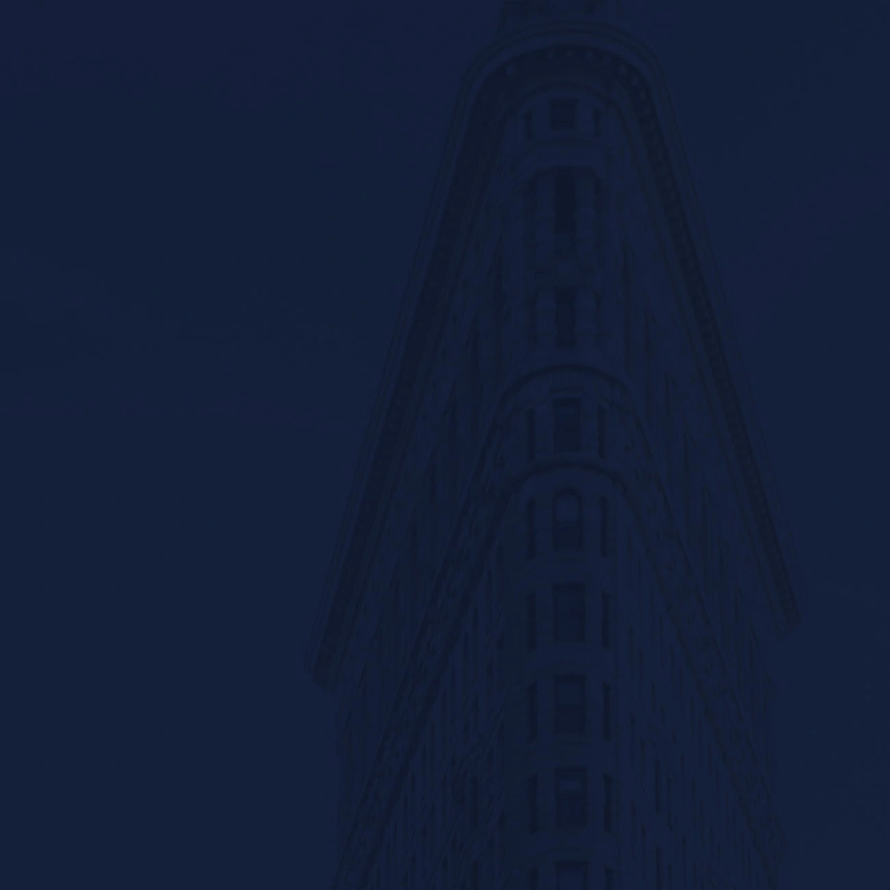 A tall, narrow, triangular building is partially visible against a dark blue background.